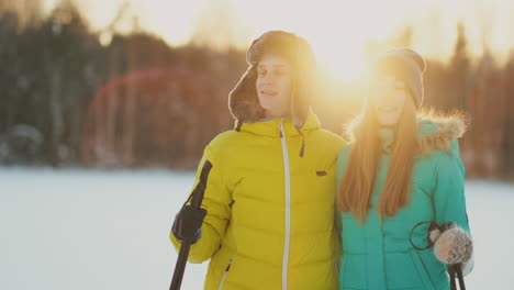 In-the-winter-forest-at-sunset-a-man-and-a-woman-ski-and-look-around-at-the-beauty-of-nature-and-attractions-in-slow-motion.
